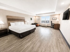 Una habitación de hotel con una cama grande, un escritorio, una silla, un televisor y una ventana con vistas.