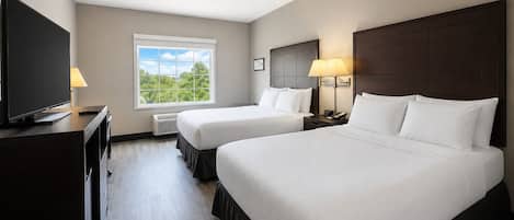 A hotel room with two beds, a television, a window with a view, and a desk with a lamp.