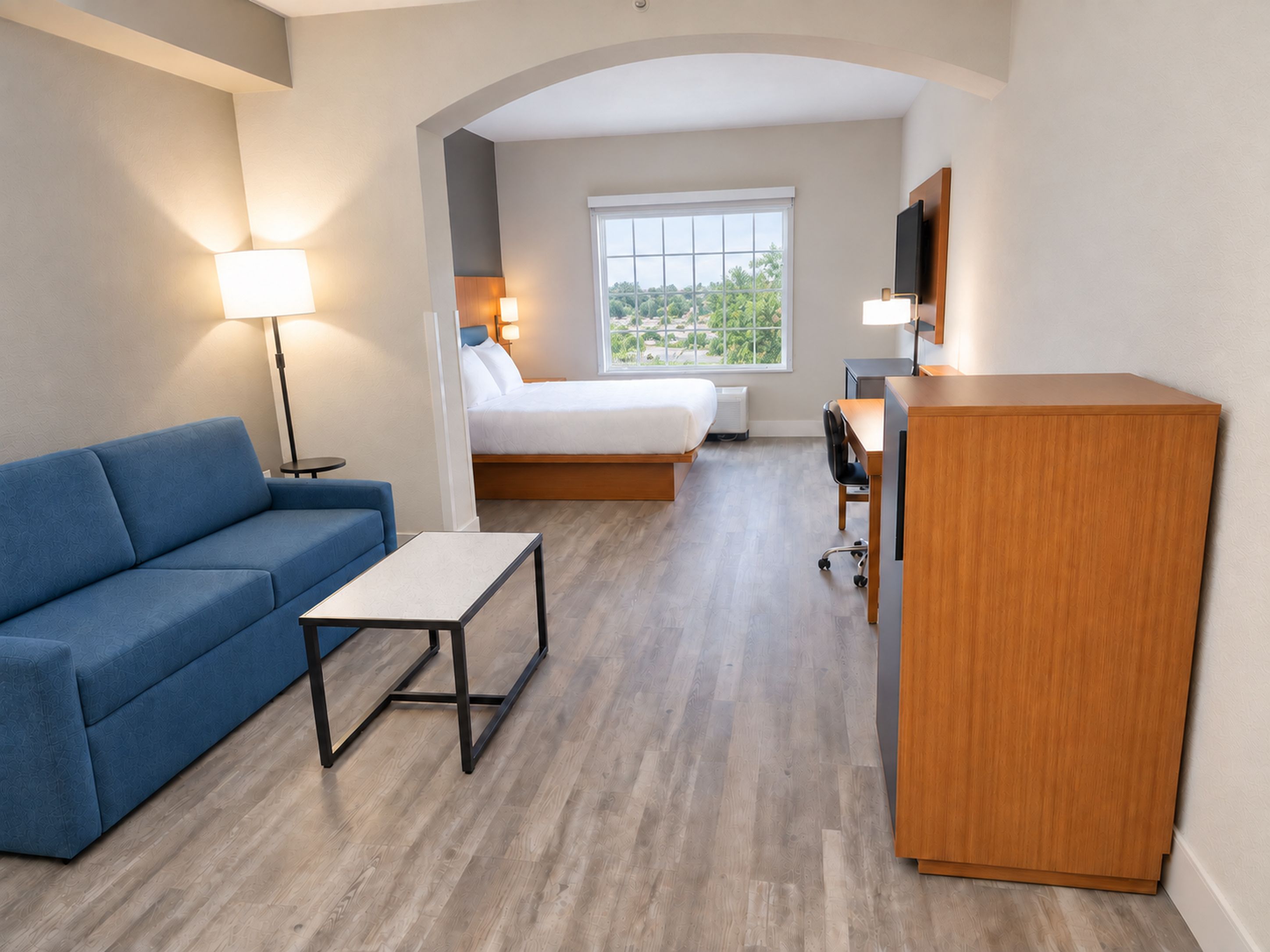 A hotel room with a sofa, a bed, a desk, and a TV.