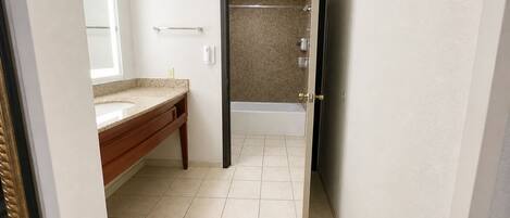 A bathroom with a vanity, a bathtub, and a shower area.