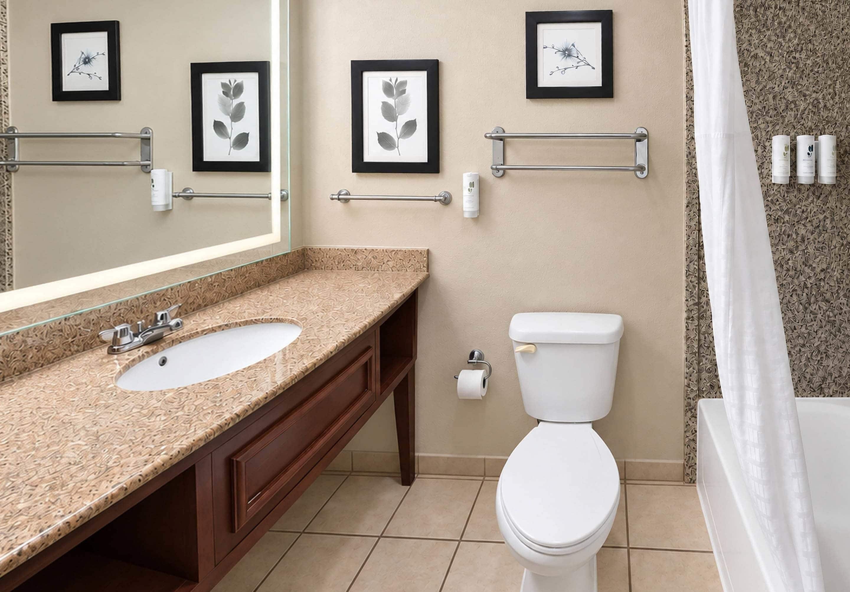 Un bagno con lavandino, specchio, WC e un quadro appeso al muro.