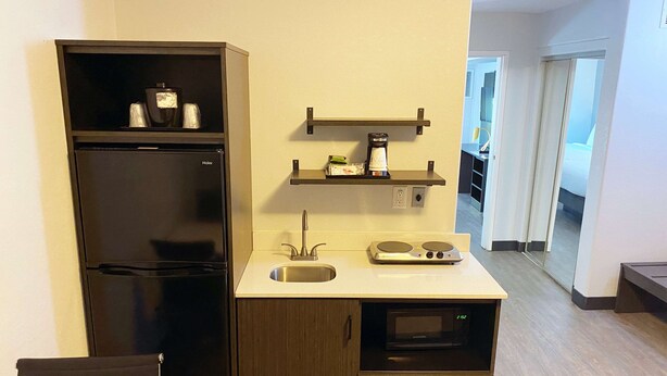 A compact kitchenette with a refrigerator, microwave, and a small sink.