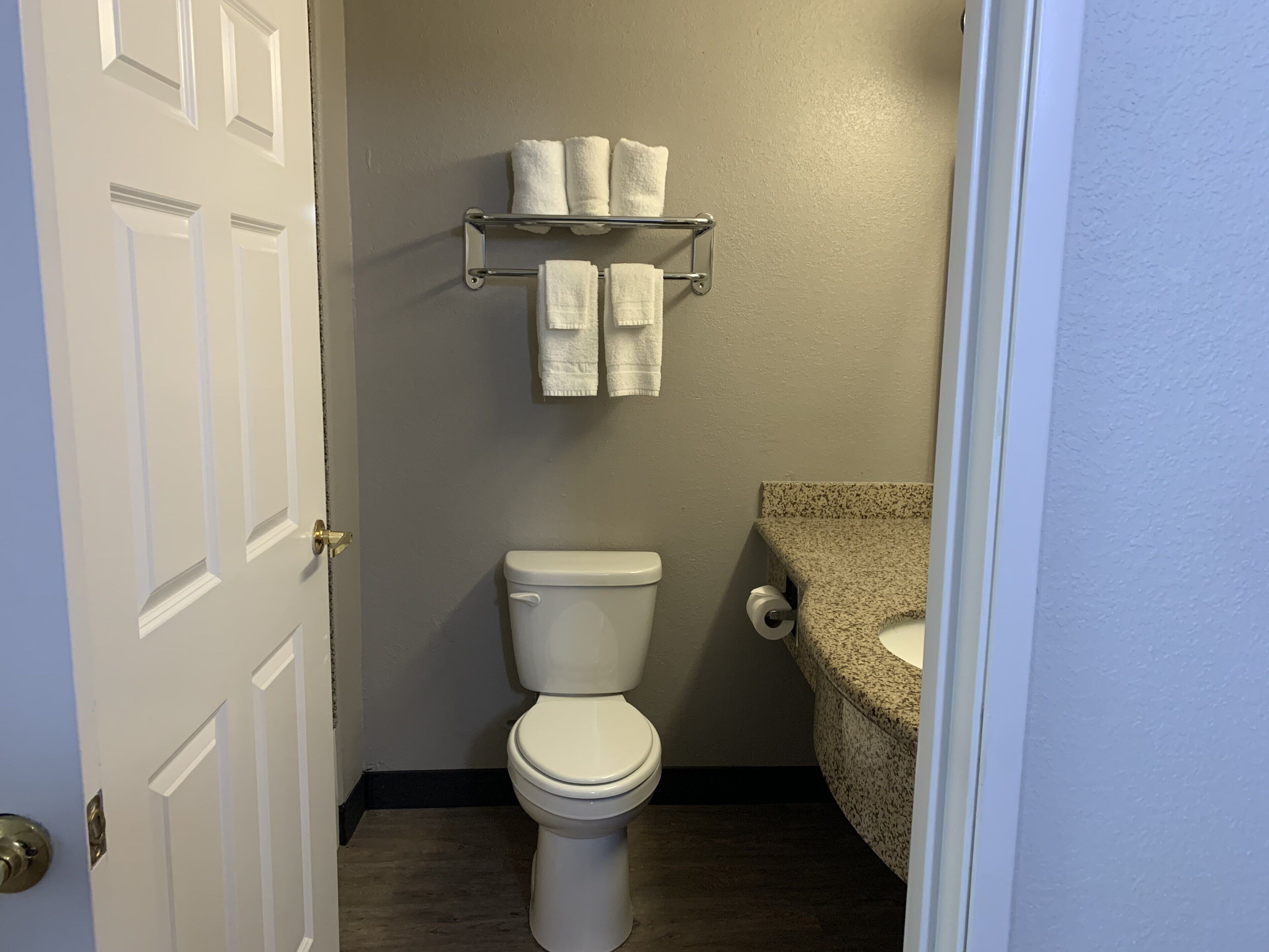 Et badeværelse med toilet, et håndklædestativ med håndklæder og en vask.