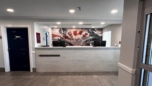 A reception area with a modern design, featuring a reception desk, a large abstract mural, and a dark door labeled "Employee Entrance."