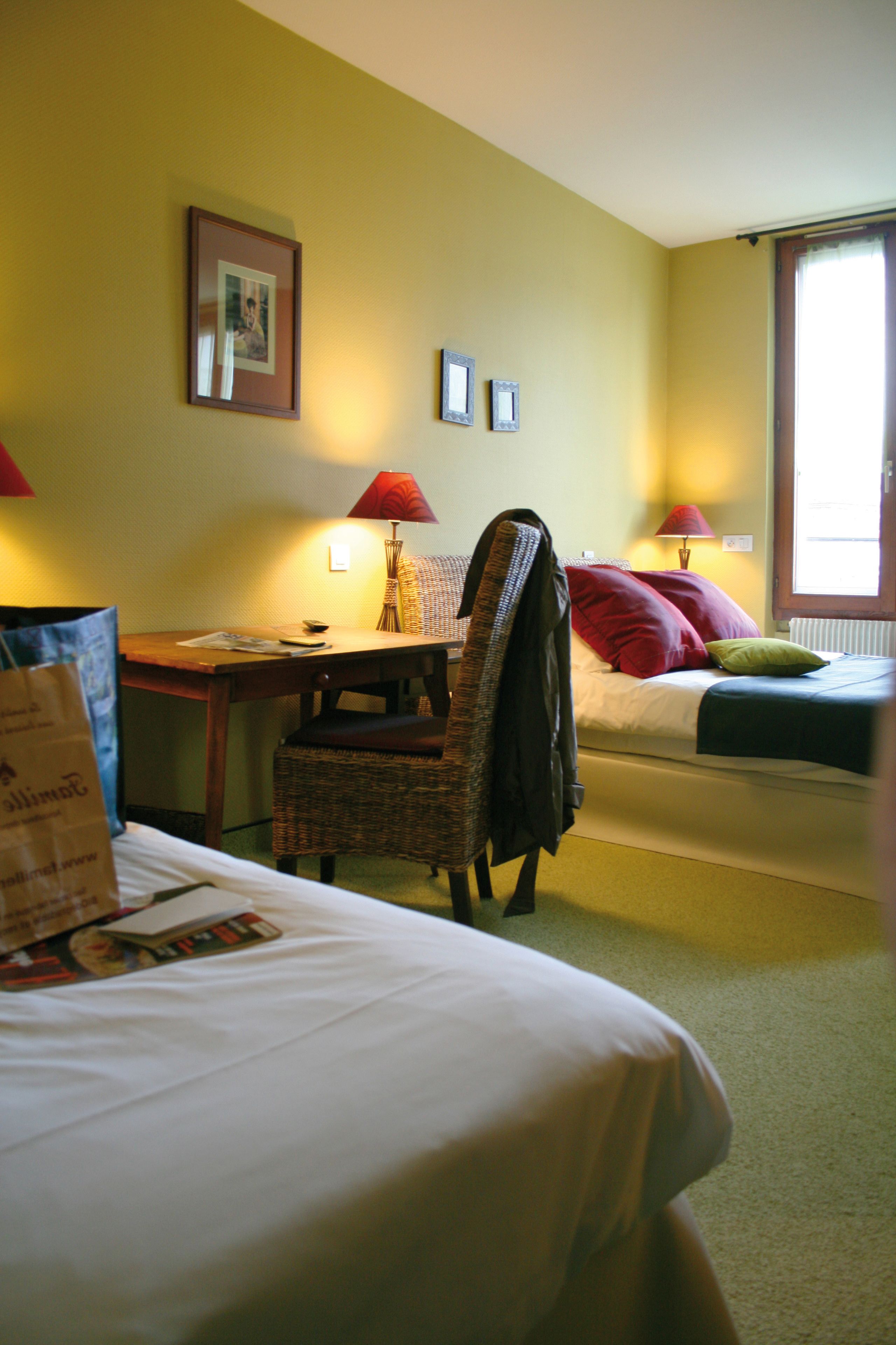A hotel room with a bed, a chair, a desk, and a window.