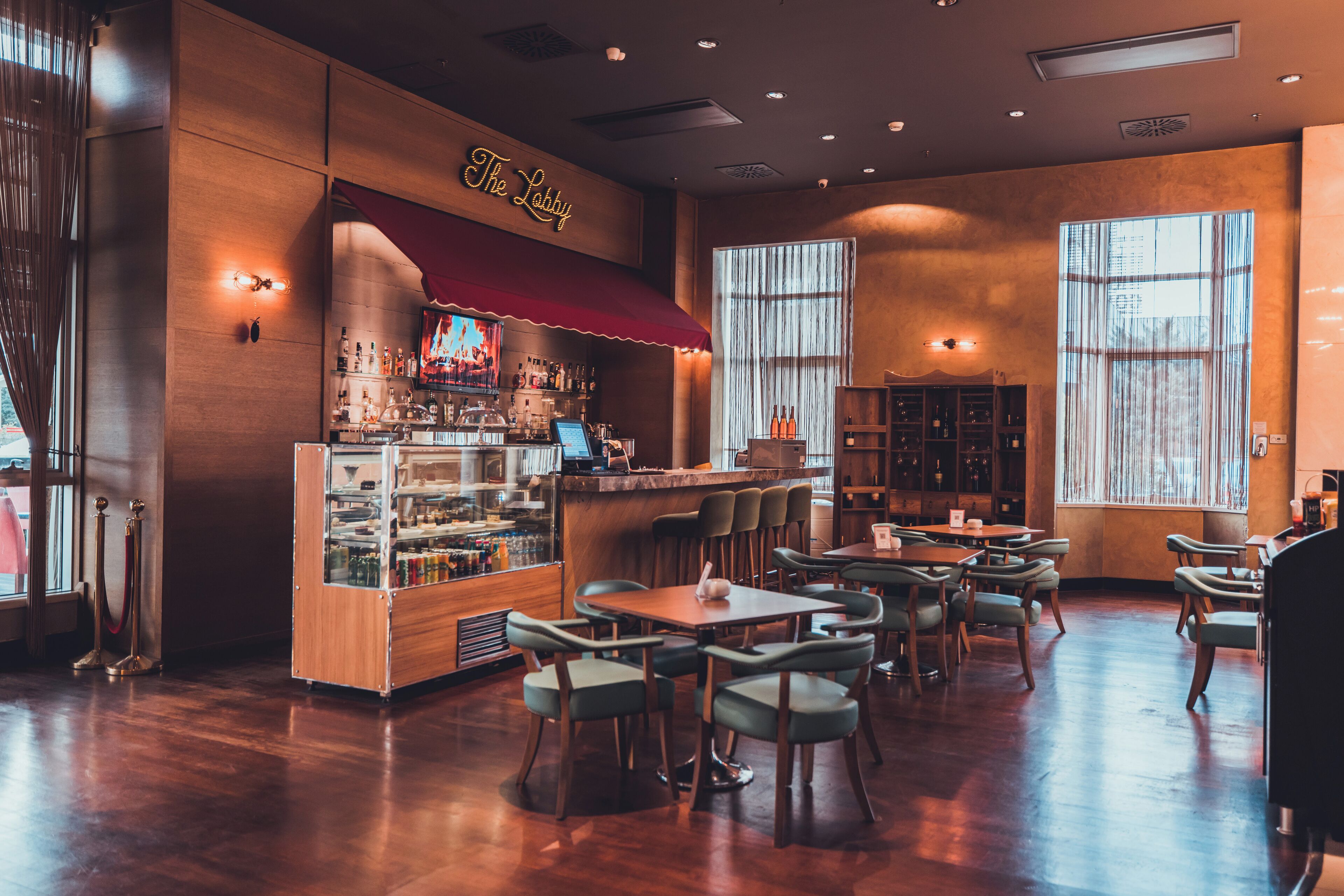 Un rincón de bar acogedor con toldo rojo, muebles de madera y una variedad de botellas en estanterías.