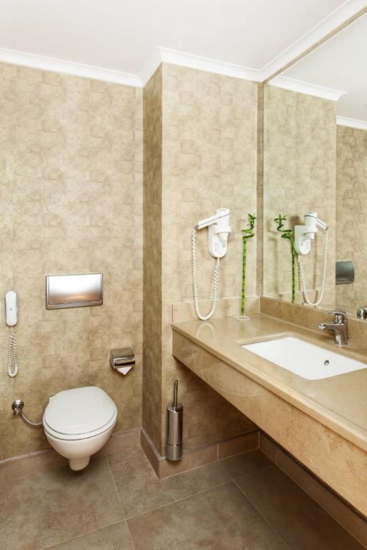 Un baño con inodoro, lavamanos, espejo y secador de pelo.