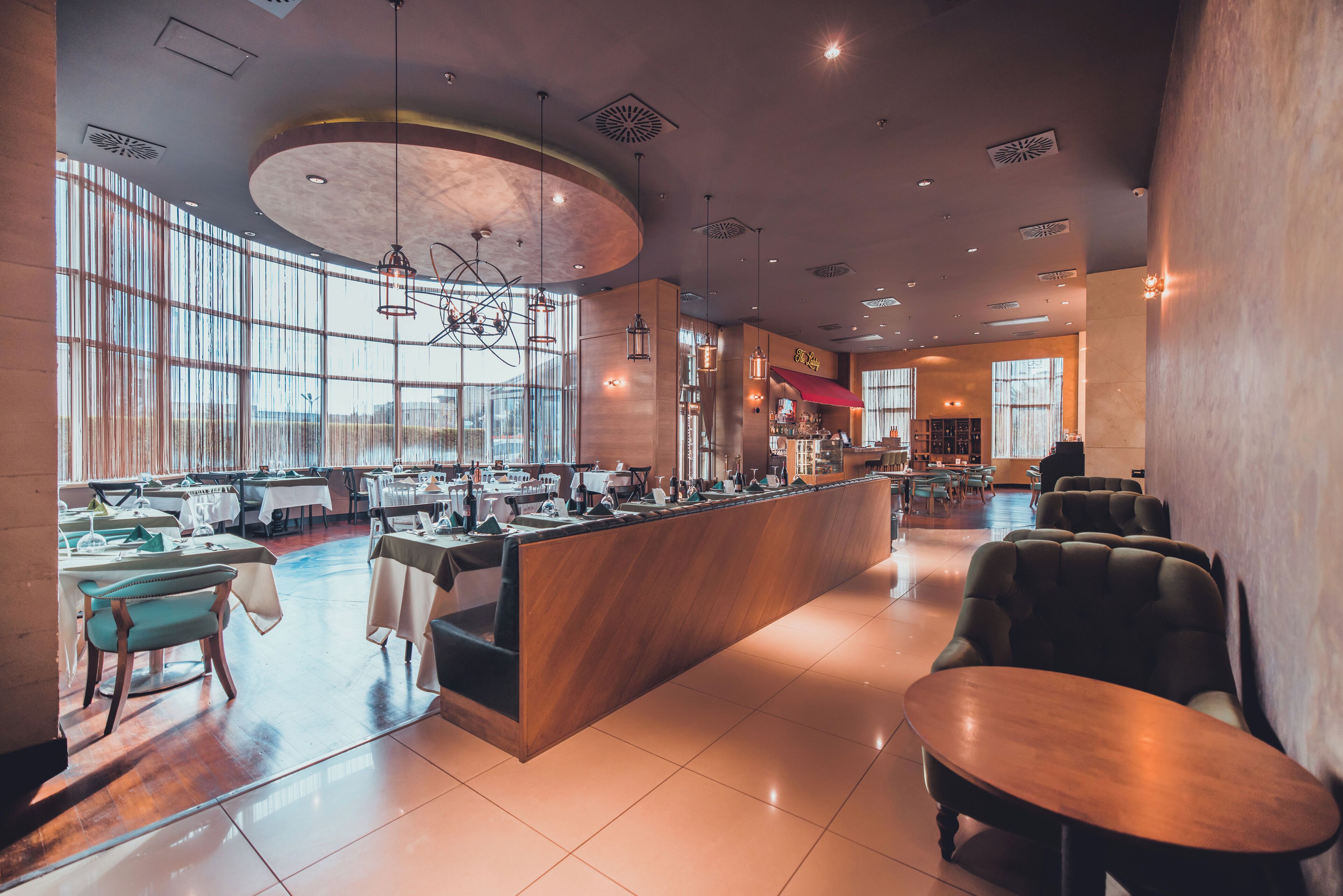Un restaurante moderno con barra central, zona de estar y amplios ventanales que aportan luz natural.