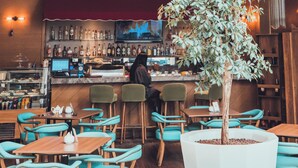 A bar area with a neon sign reading "The Lobby," a bartender, and a large potted tree. - WOW Airport Hotel (Istanbul)
