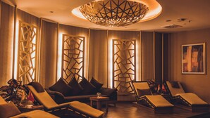A spa room with wooden floors, multiple lounge chairs, and a unique ceiling light fixture. - WOW Airport Hotel (Istanbul)