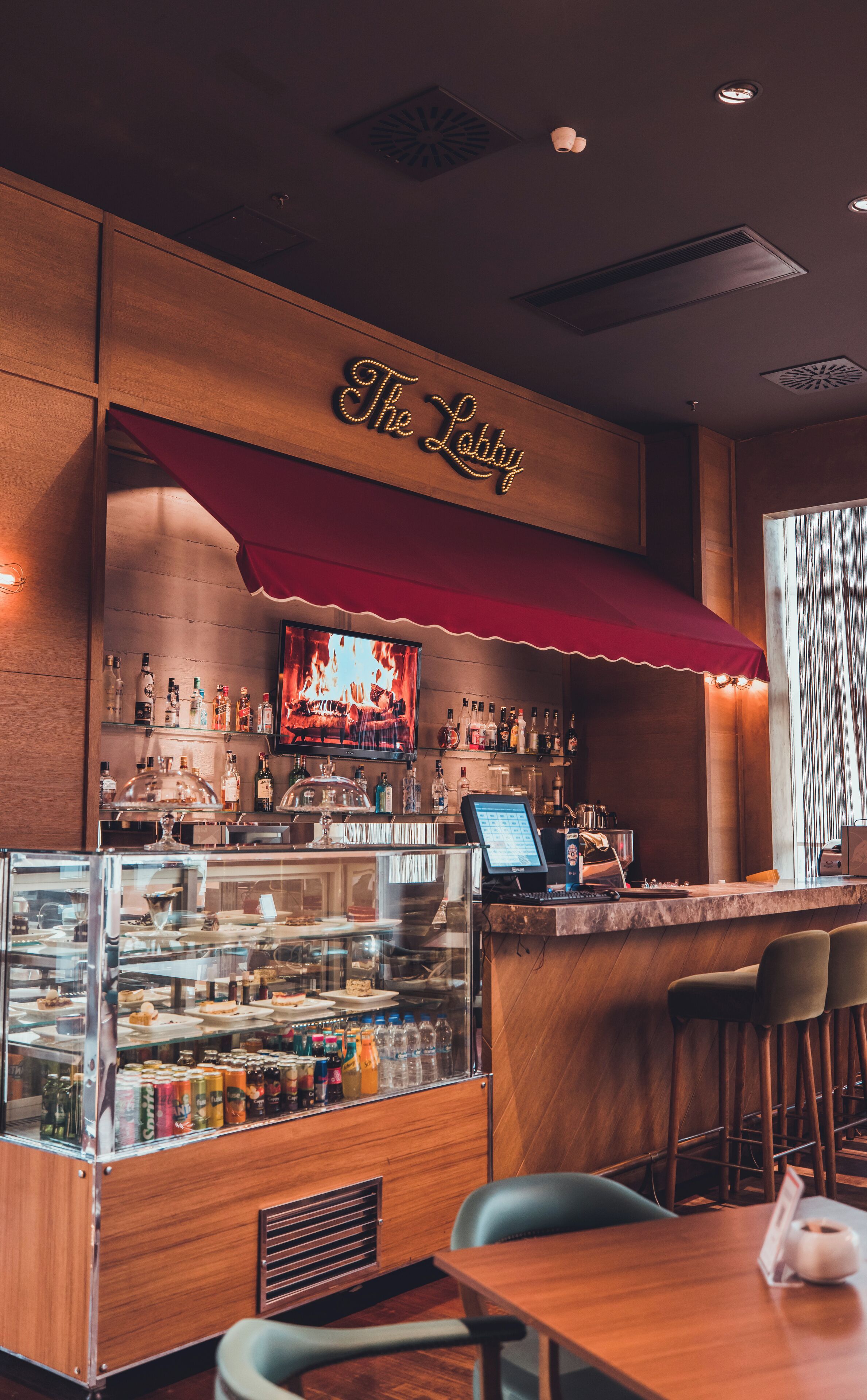 A bar area with a wooden counter, a glass display case with snacks, and a red awning above the bar.