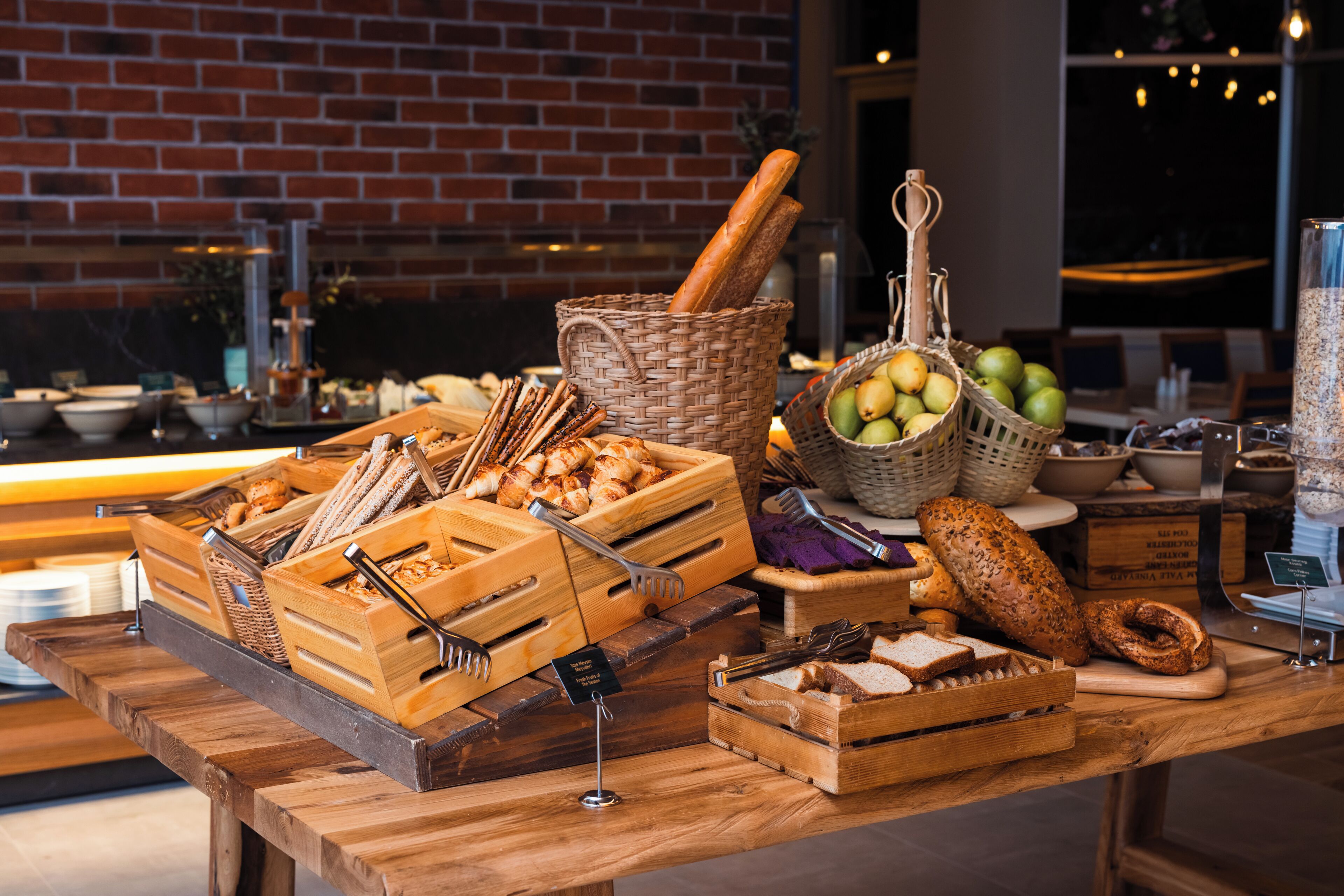 A buffet setup with various food items and utensils on a wooden table.