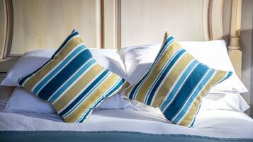 A bed with white linens and striped pillows.