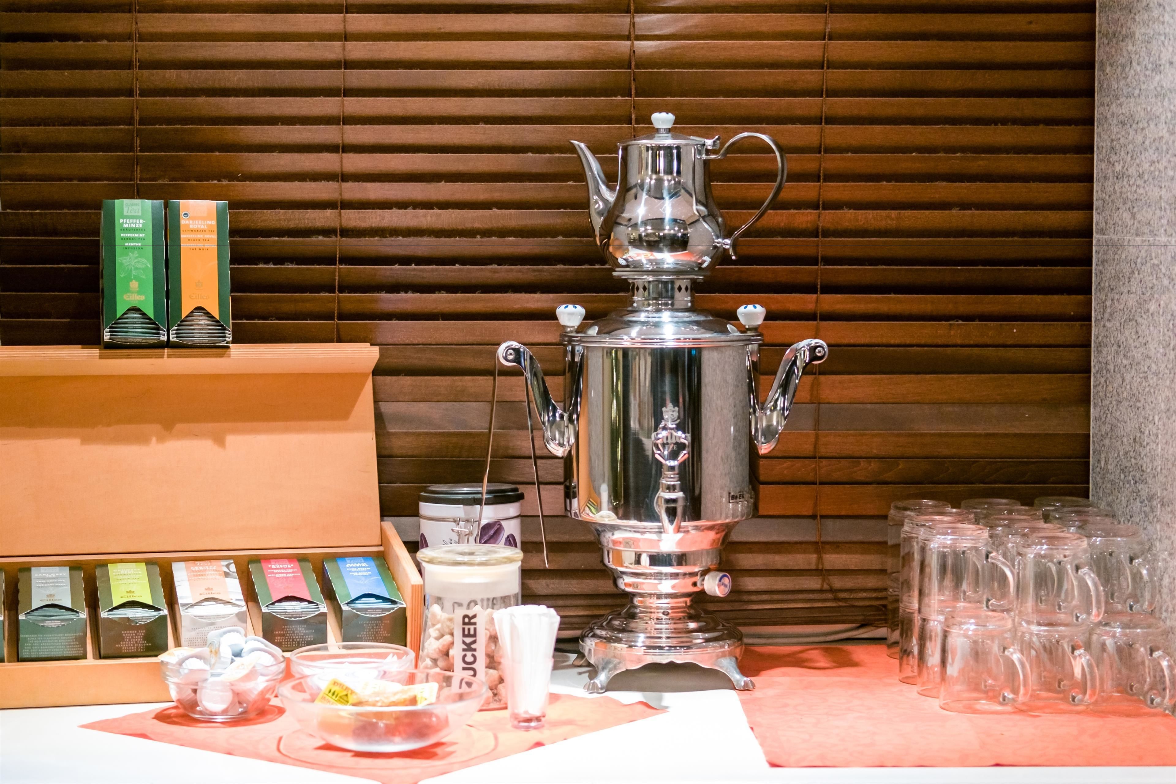 Un samovar tradicional con vajilla para té y vasos sobre una mesa.