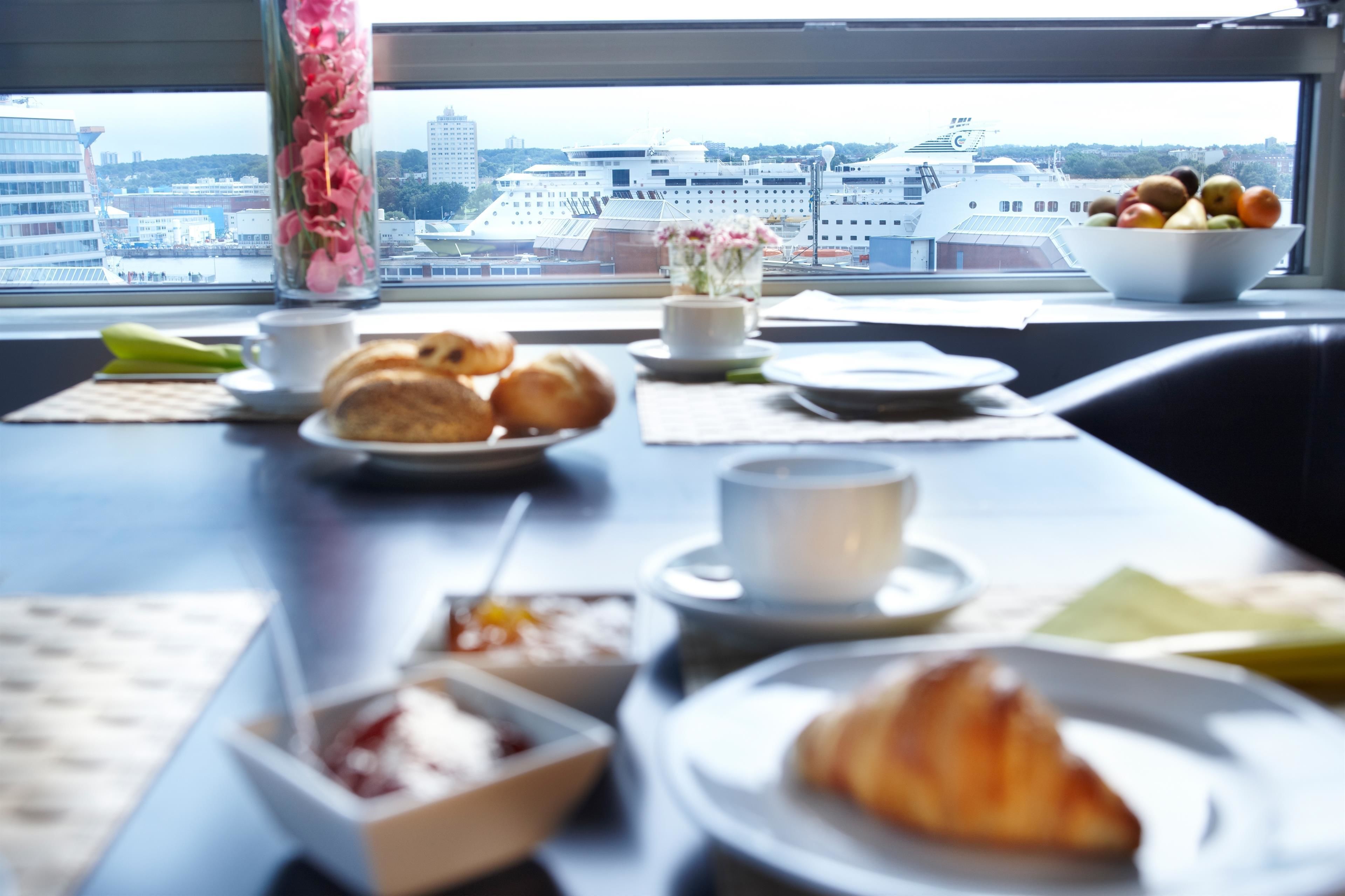 A breakfast table with croissants, a bowl of fruit, and a vase with flowers.