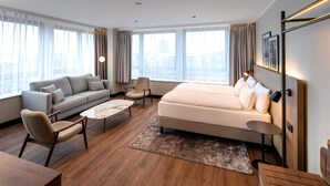 A modern hotel room with a sofa, armchair, and a bed. - Hotel Astor Kiel by Campanile (Kiel)