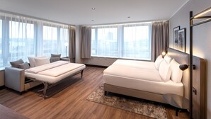 A modern hotel room with a bed, sofa, and a desk. - Hotel Astor Kiel by Campanile (Kiel)