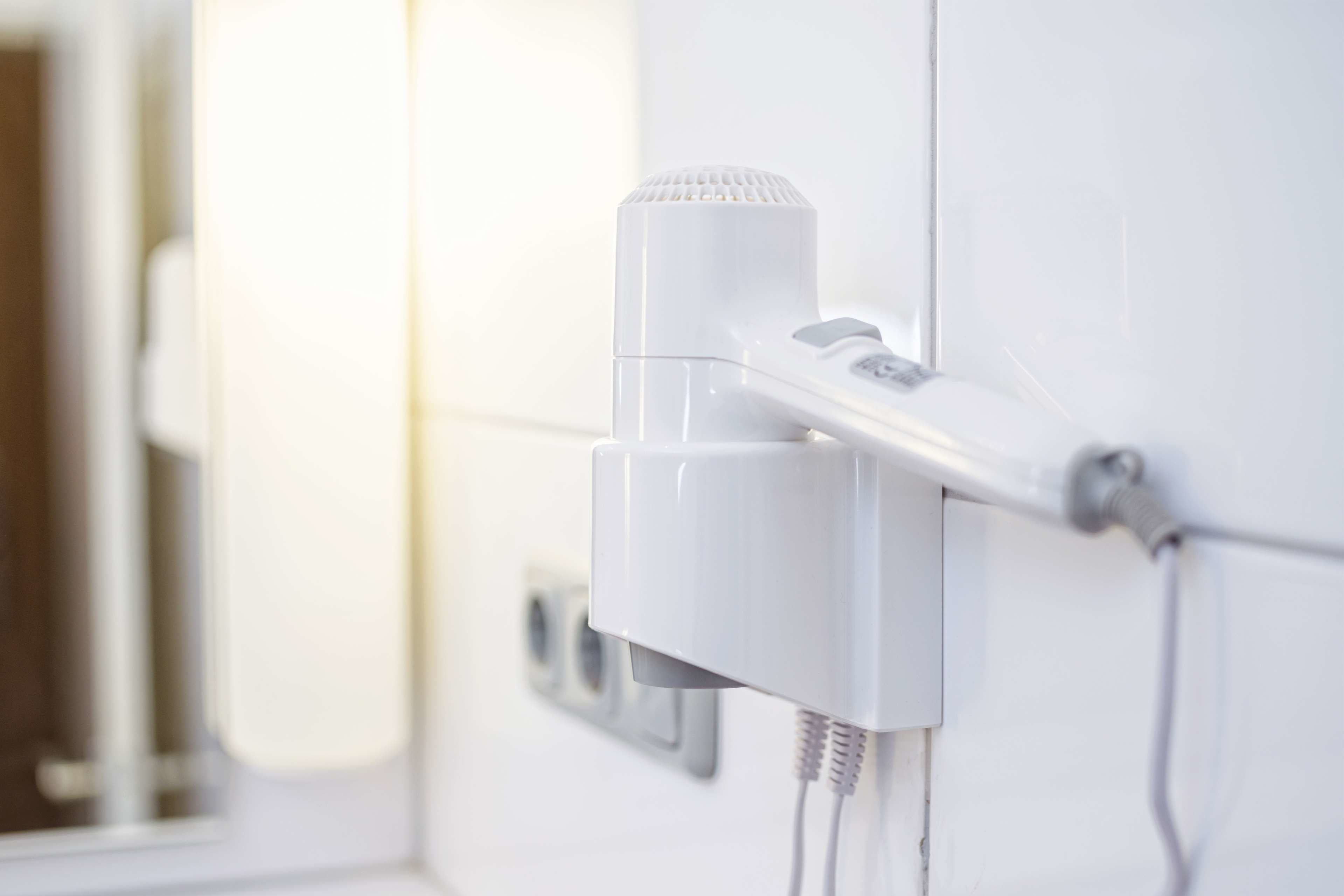 Un secador blanco fijado a la pared con un enchufe y un cable.