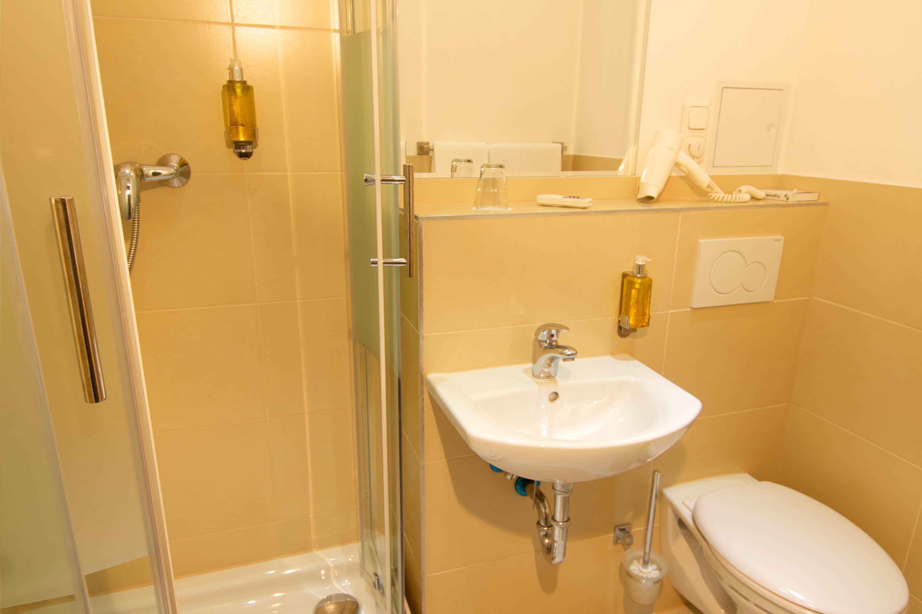 Un bany amb un plat de dutxa de vidre, un lavabo blanc i un vàter.