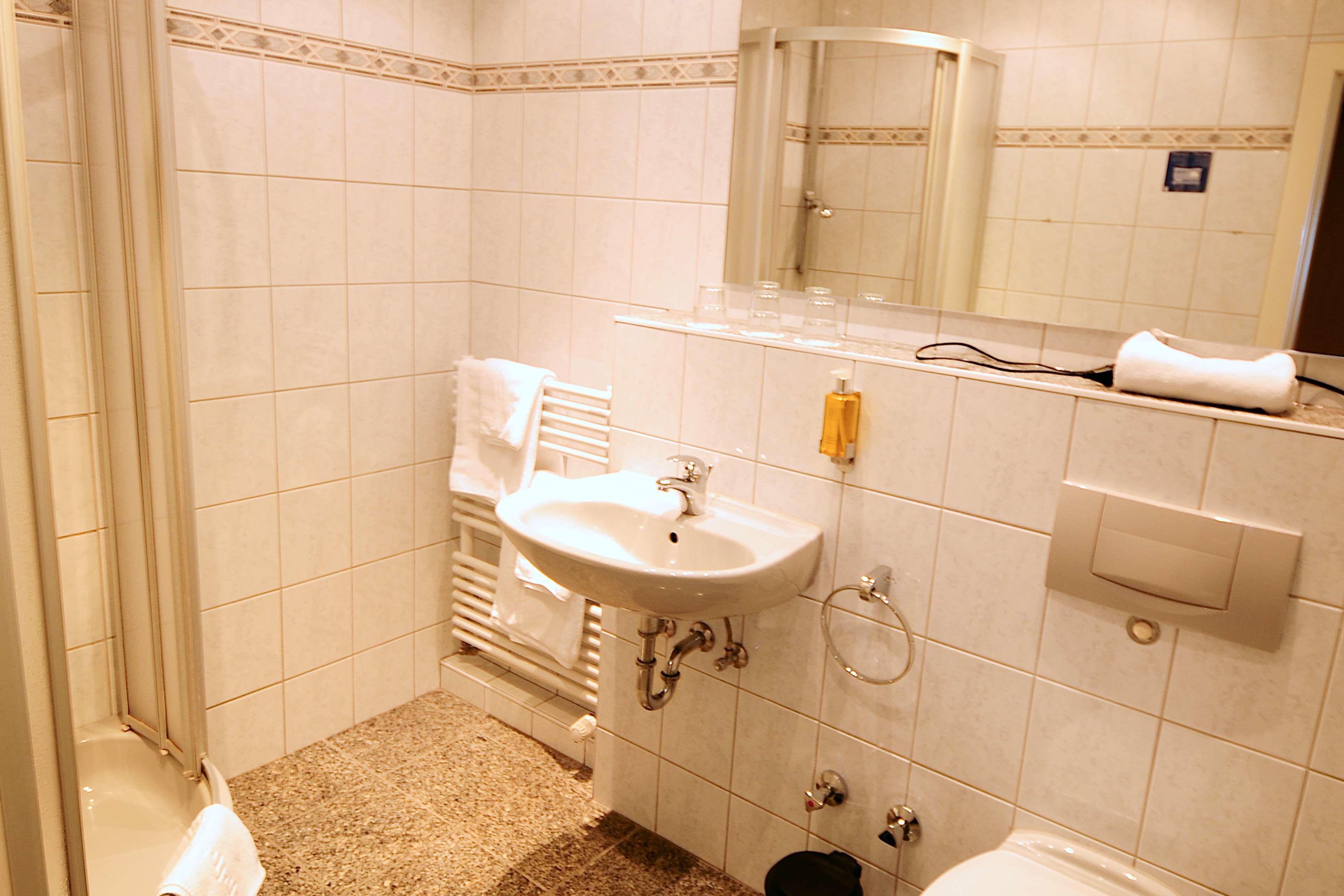 A bathroom with a sink, mirror, towel rack, and shower.