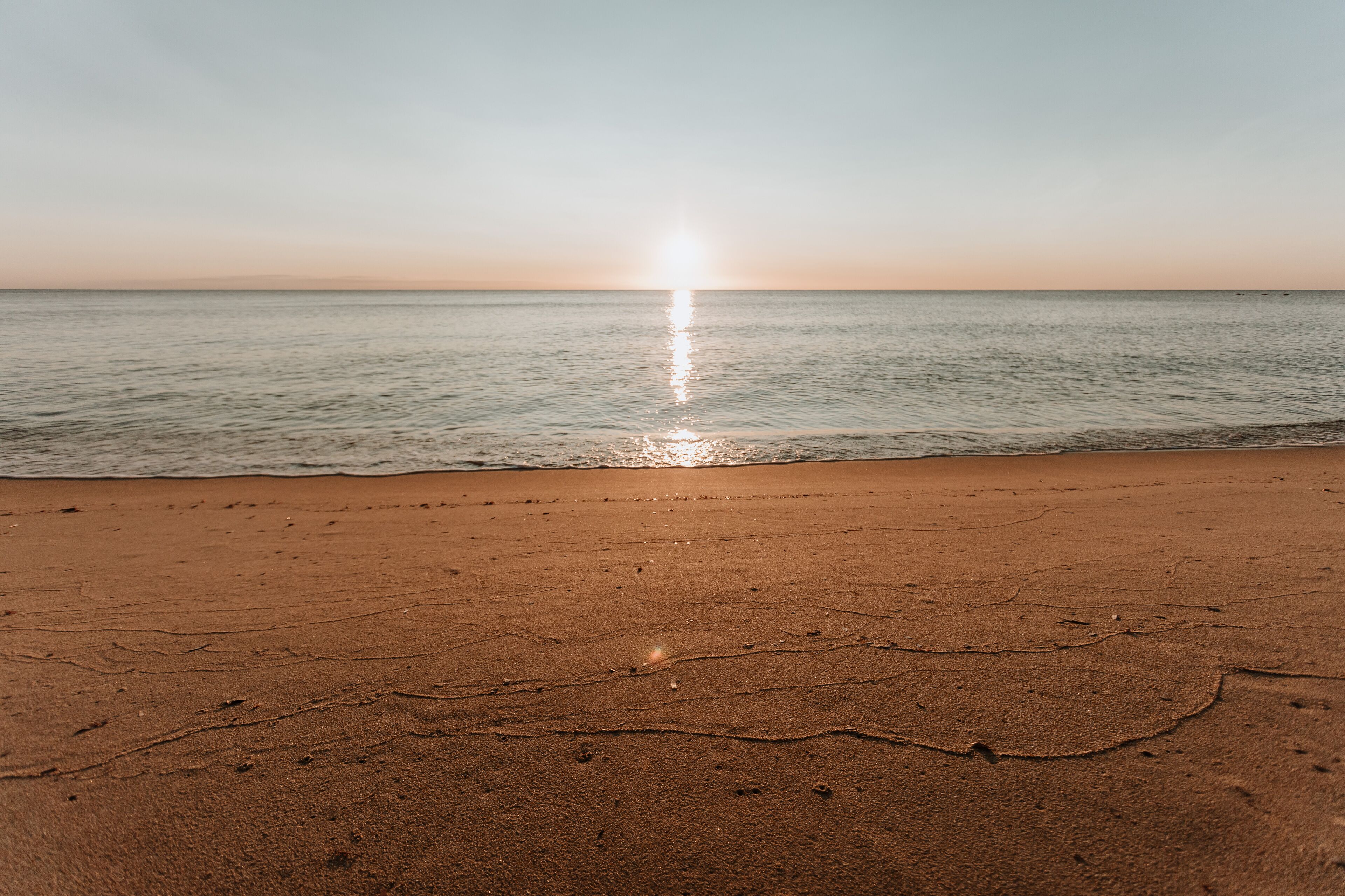 Una playa con un atardecer sobre el océano.