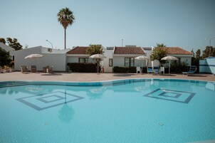 Una piscina al aire libre de temporada, sombrillas, tumbonas