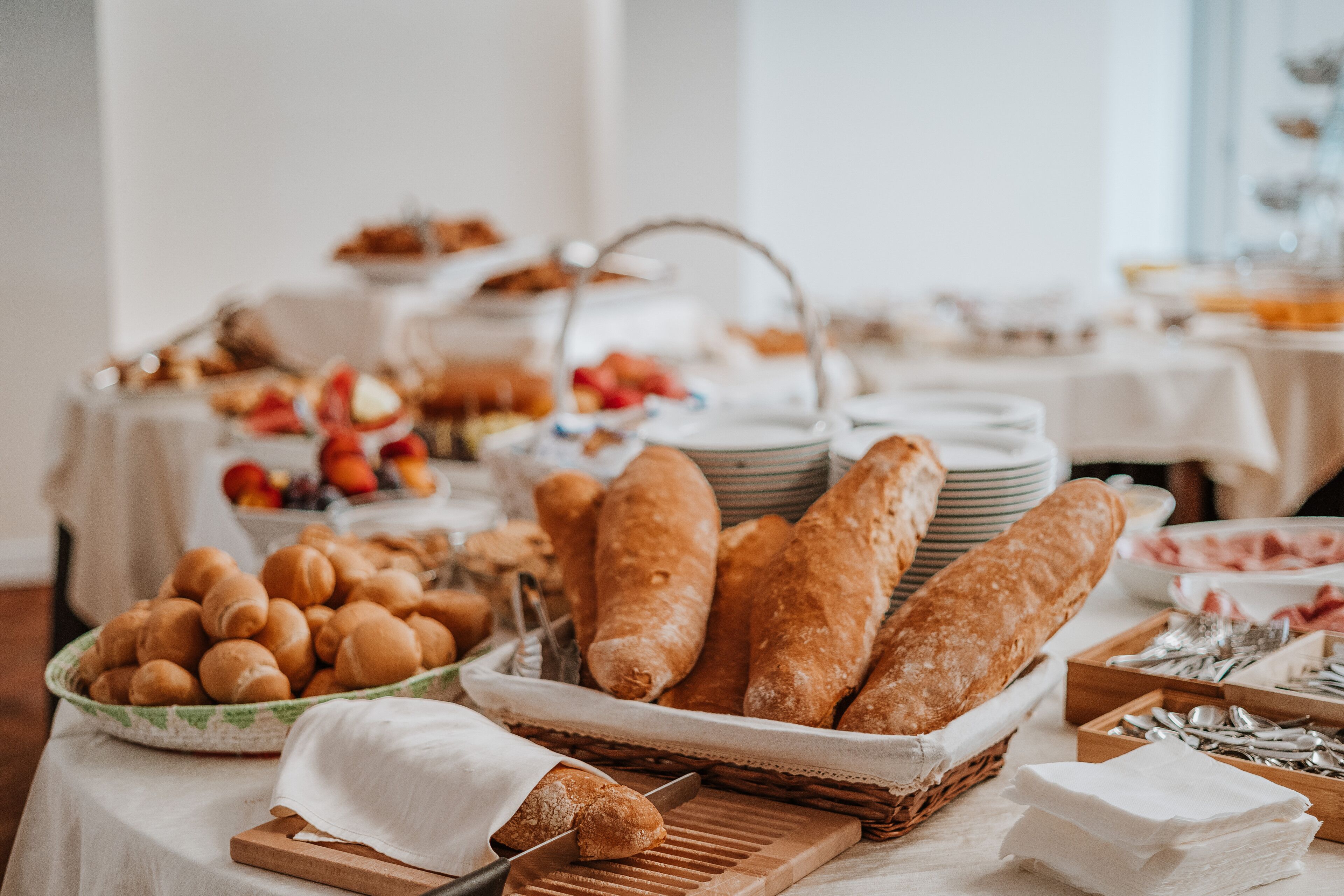 A buffet table with various breads, pastries, and fruits.