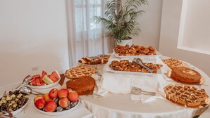 Una mesa de buffet con diversas opciones de comida, entre ellas frutas, pasteles y un pastel.