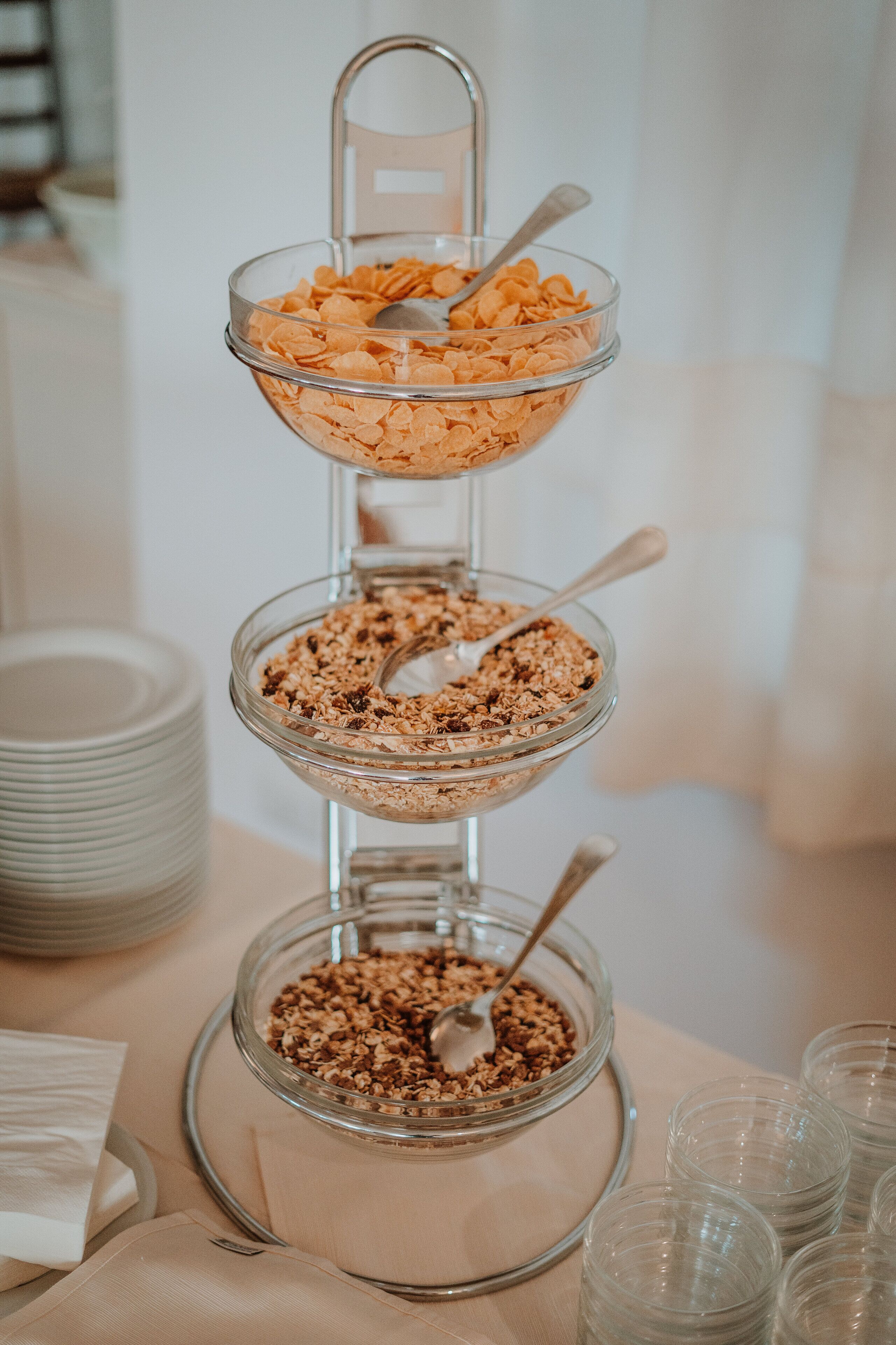 Un recipiente de vidrio de tres niveles con diferentes tipos de cereales y granola.