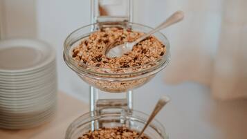 Un recipiente de vidrio de tres niveles con diferentes tipos de cereales y granola.