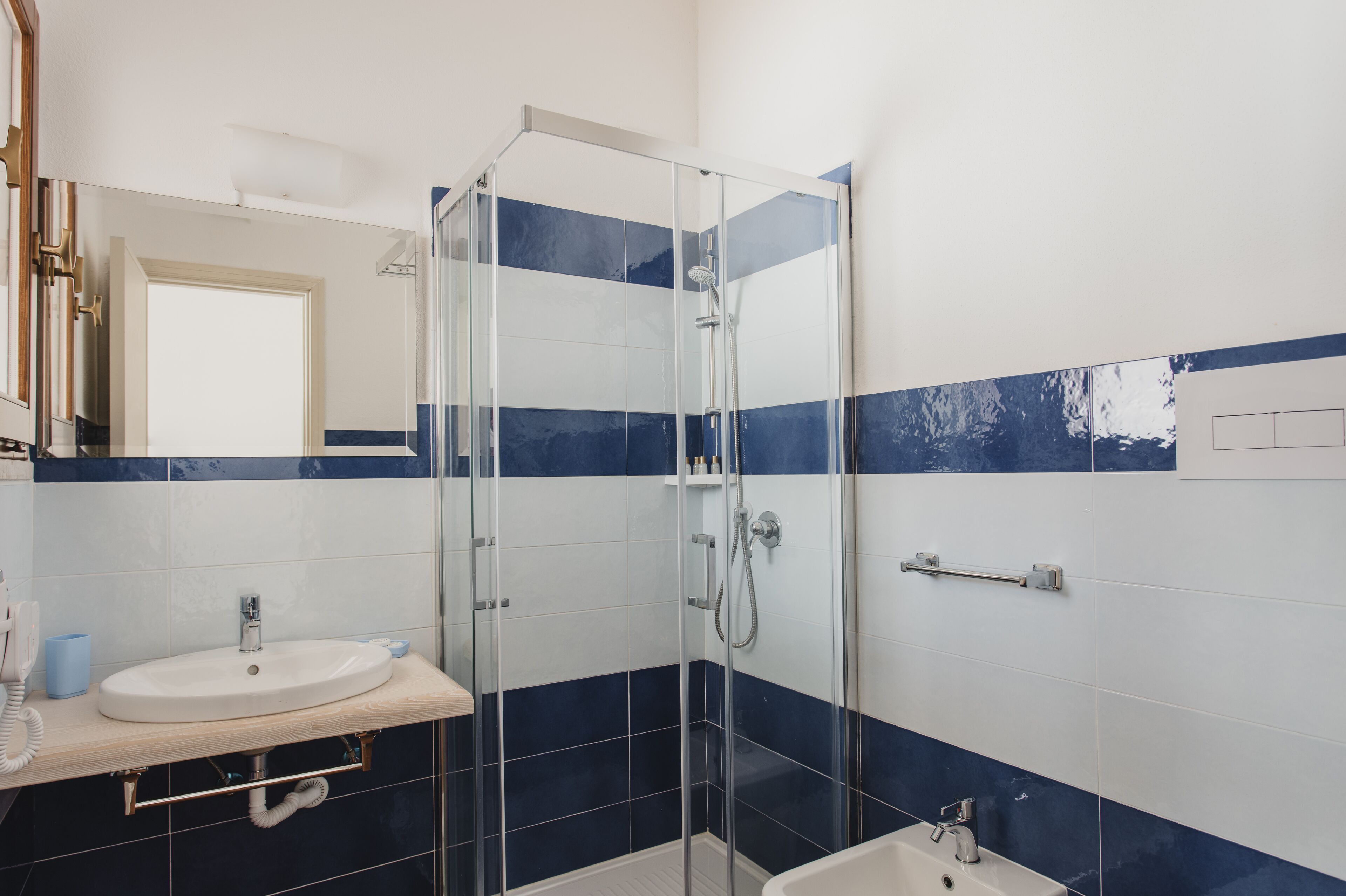 A bathroom with a glass-enclosed shower, a sink, and a mirror.