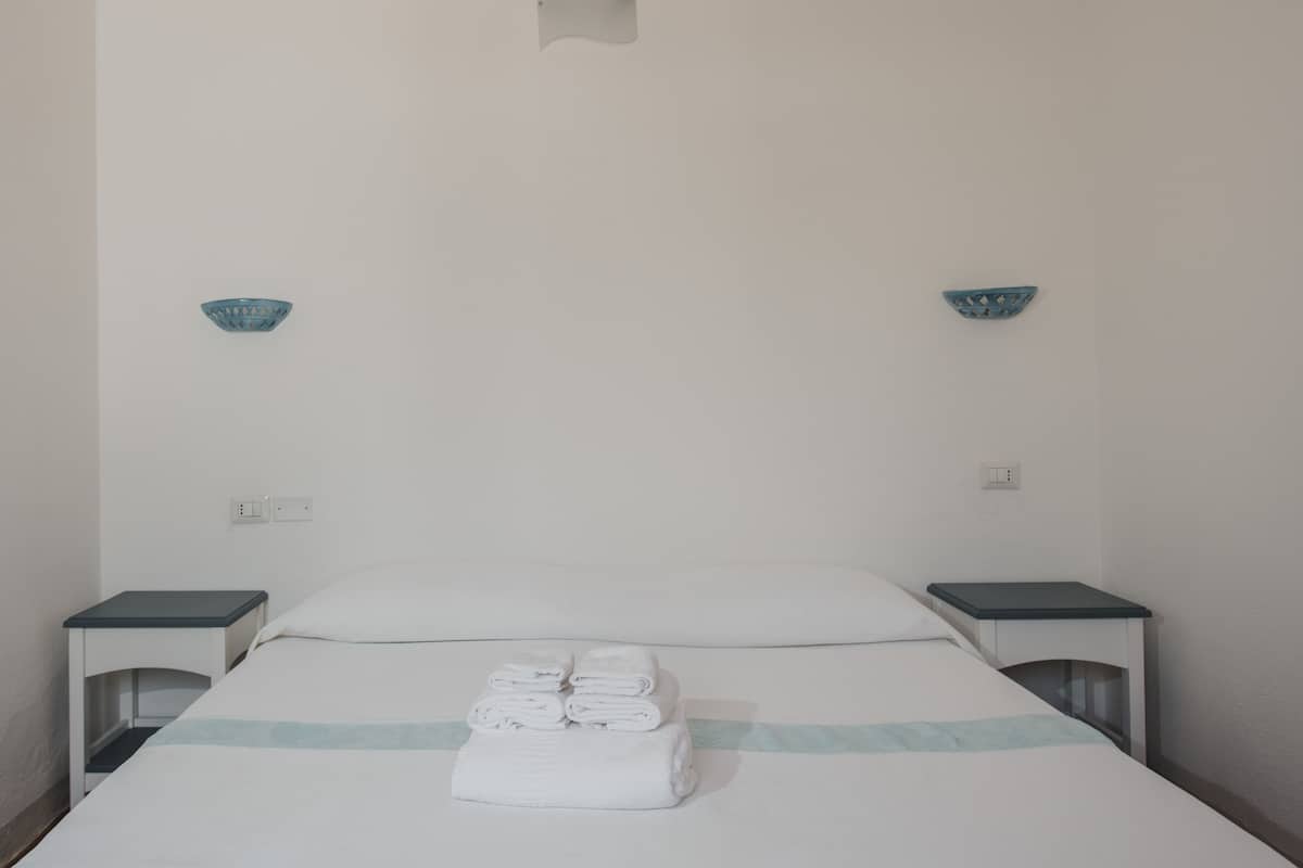 A hotel room with a bed, two nightstands, and two wall-mounted light fixtures.
