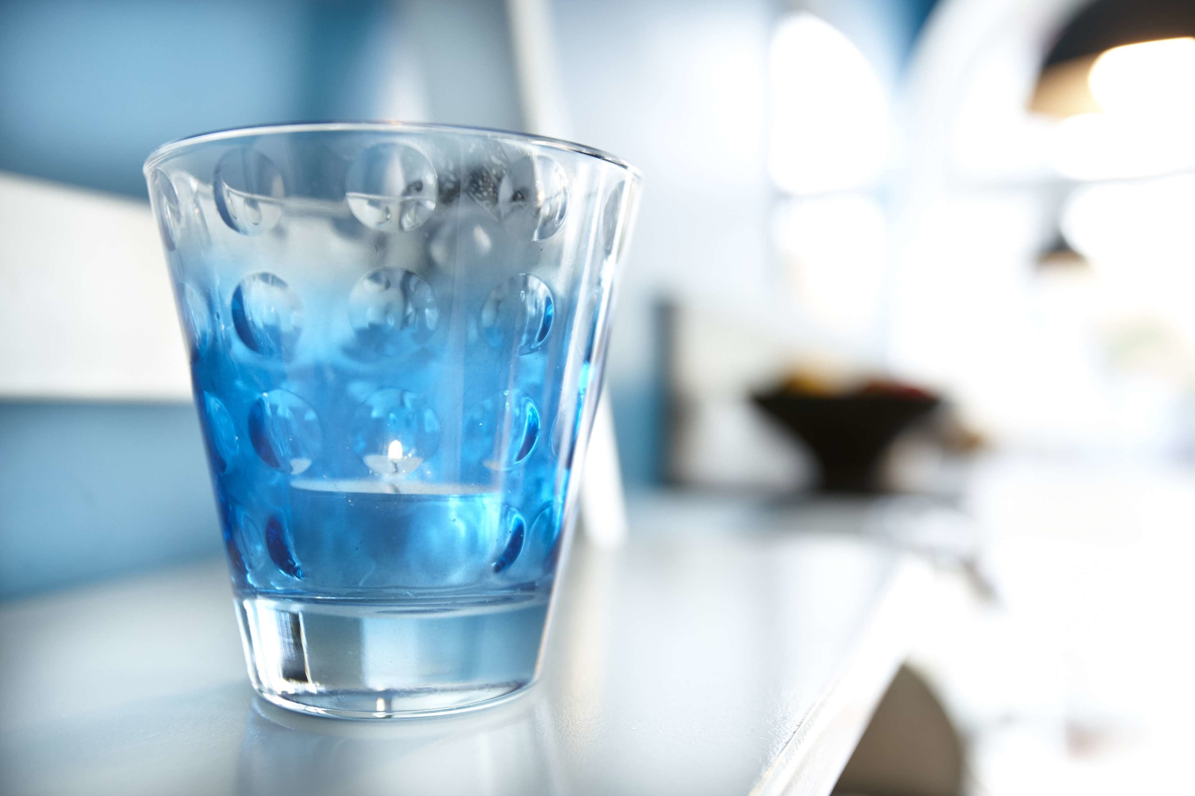 A clear glass with a blue tint on a reflective surface.