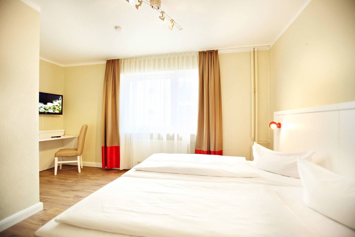 Une chambre d’hôtel avec un lit, un bureau et une télévision.