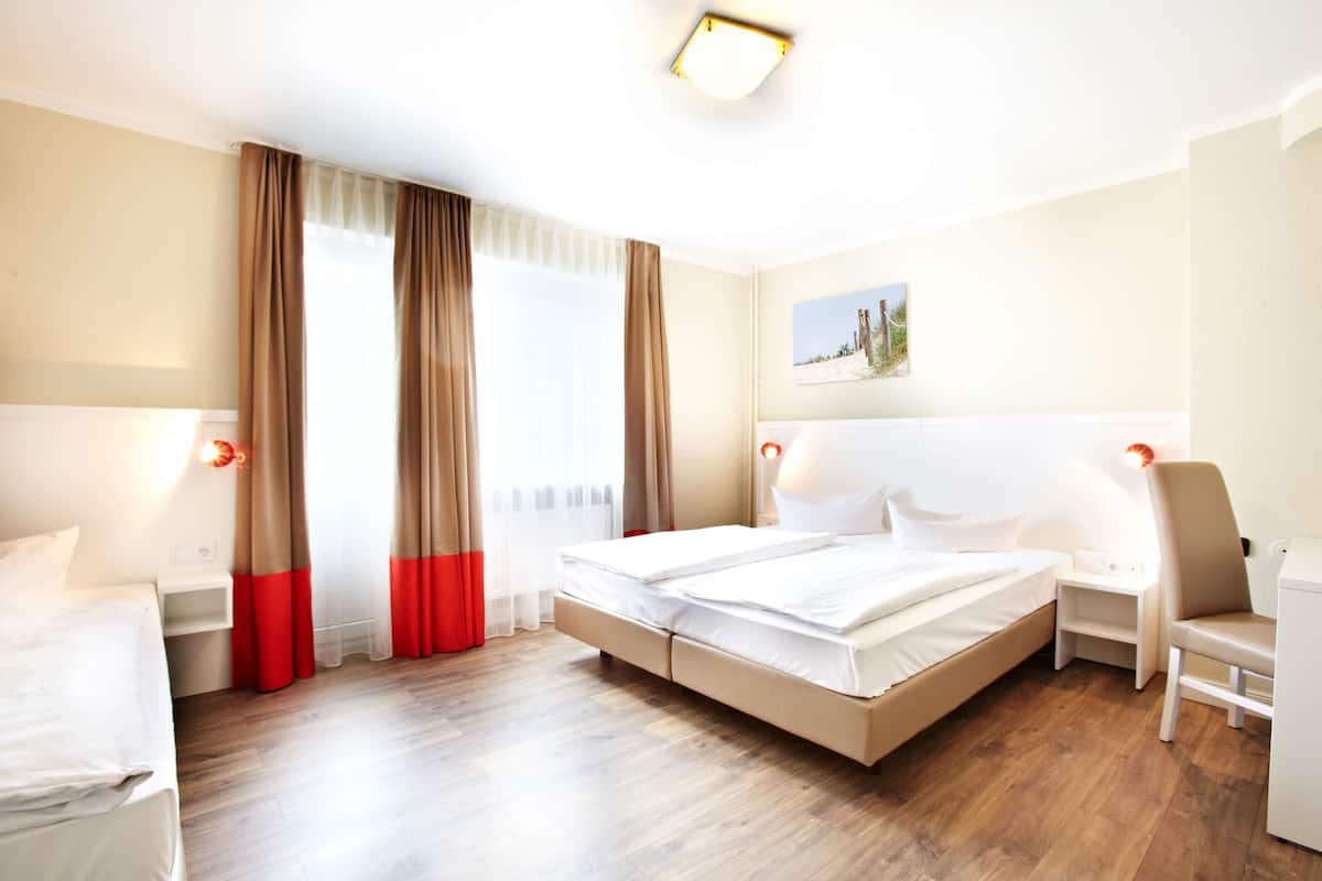 Une chambre d’hôtel avec un grand lit, des tables de chevet, une chaise et un tableau au mur.