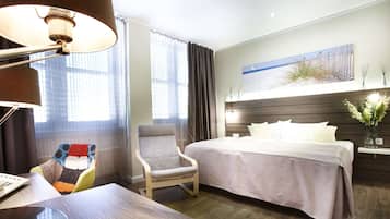 Een hotelkamer met een bed, een stoel, een bureau en een lamp.