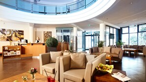 Een ruime lobby met een receptiebalie, een zithoek en grote ramen.