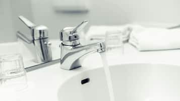 A modern bathroom sink with a chrome faucet and clear glass soap dispenser.