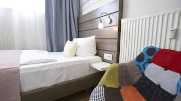 Een opgemaakt bed met witte lakens, een houten hoofdbord en een nachtkastje met een lamp.