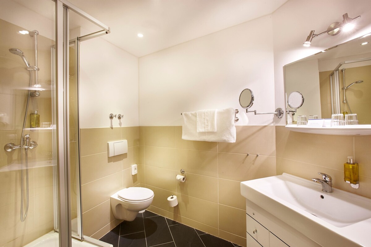 Une salle de bain moderne avec une douche à parois de verre, des toilettes blanches, un lavabo avec un miroir et un porte-serviettes.