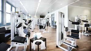 Een sportschool met diverse trainingsapparaten, een waterfles en handdoeken op een tafel.