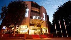 Een hotel met een opvallende ingang, een trap naar de hoofdtoegang en een groot bord waarop 