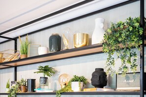 Une étagère ornée de divers objets décoratifs, notamment des plantes, des vases et une sculpture.