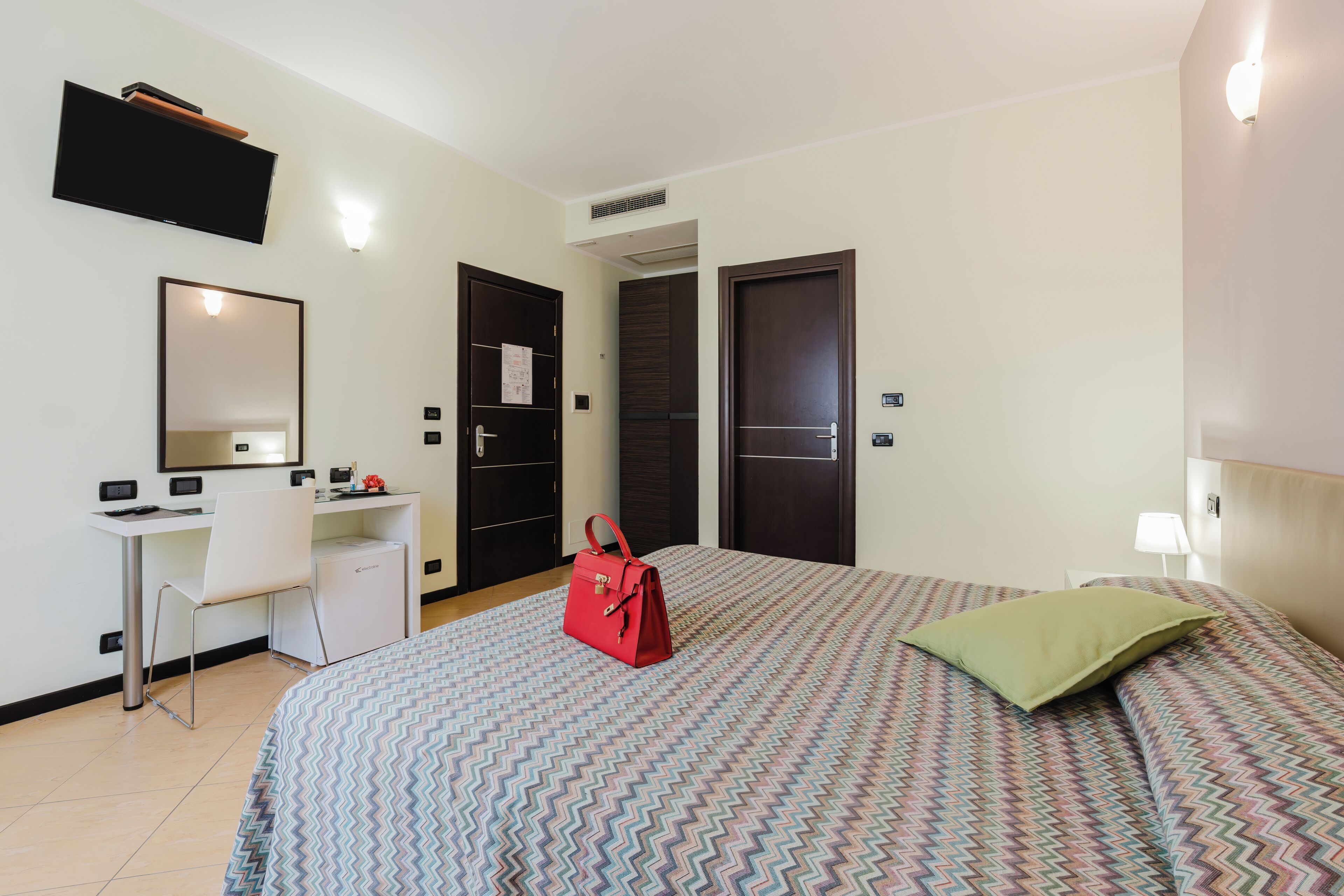 Une chambre d’hôtel équipée d’un lit, d’un bureau, d’une chaise et d’une armoire.