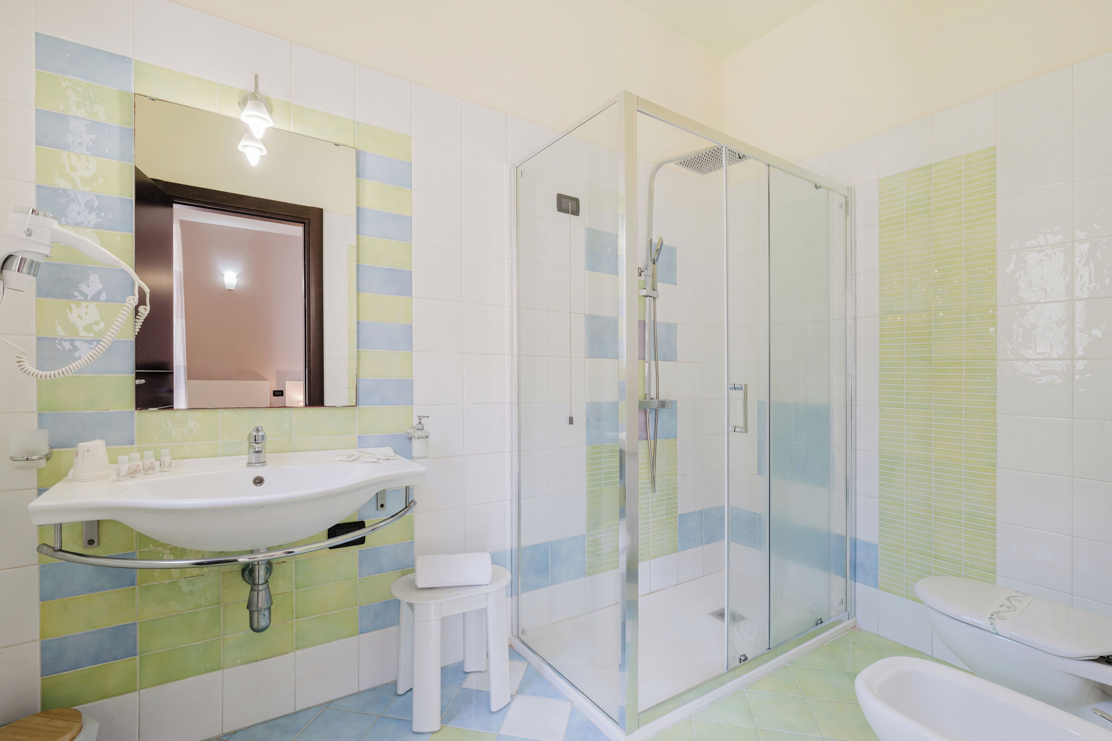 Un bagno con doccia vetrata, lavandino con specchio e water.