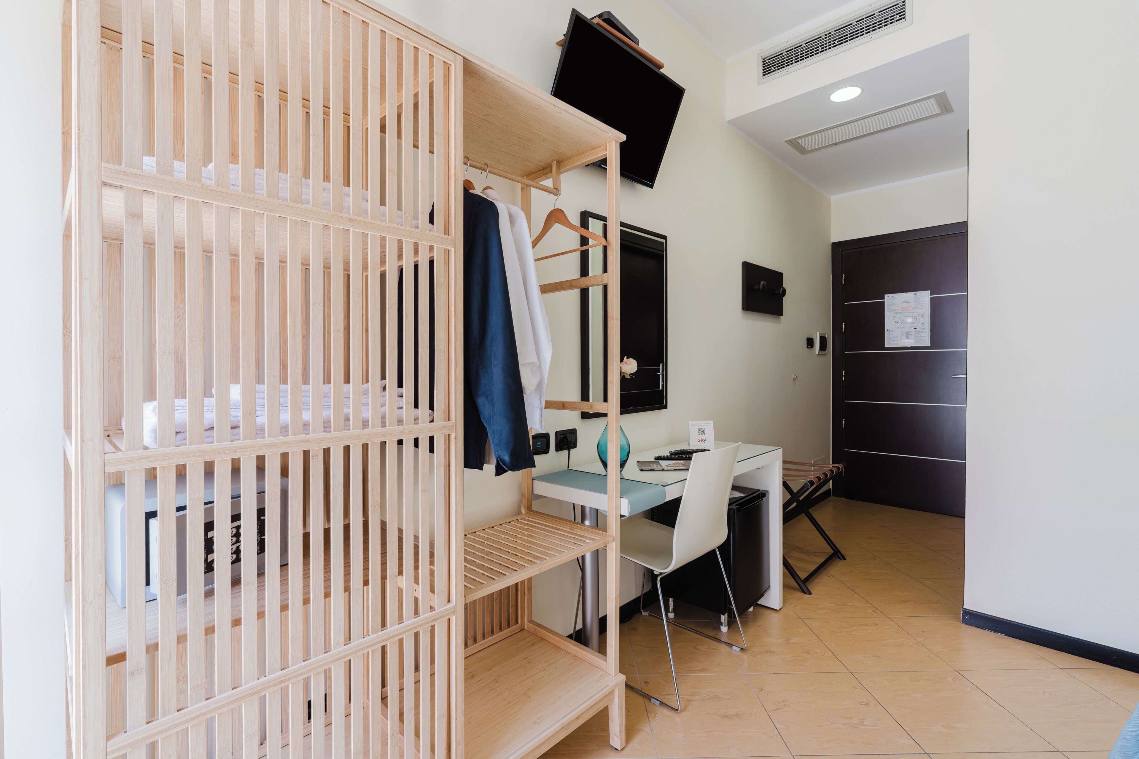 A room with a bunk bed, a desk, a chair, a television, and a door with a notice.