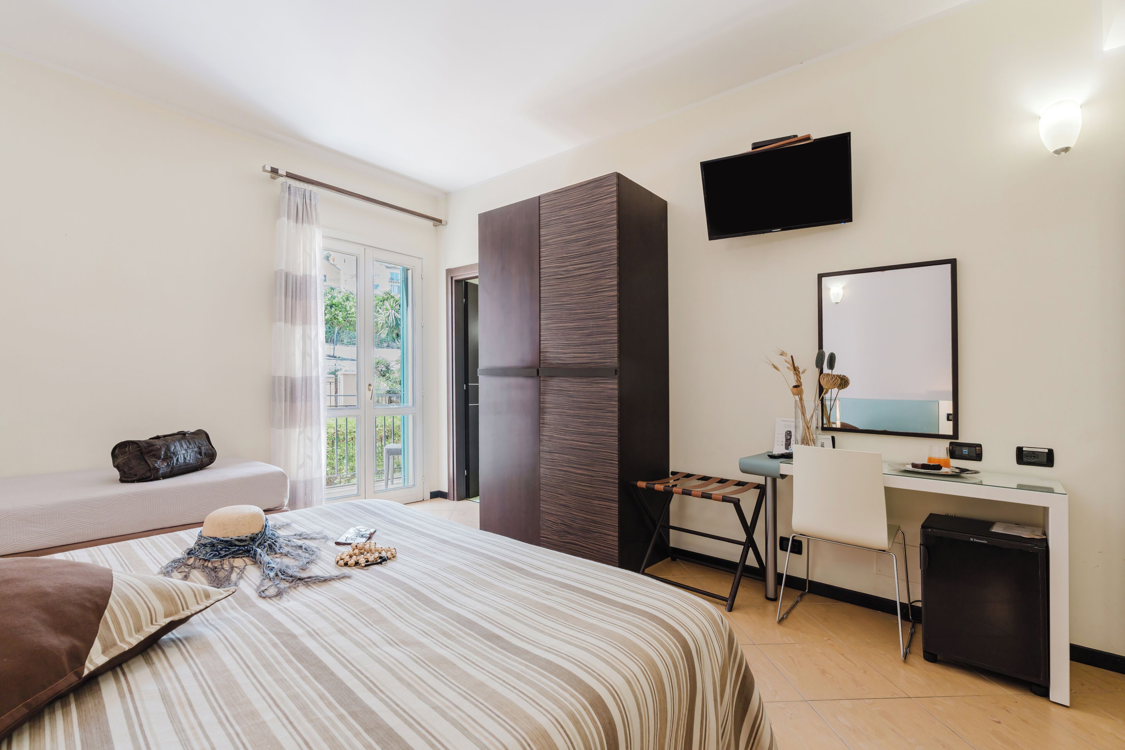 A modern bedroom with a bed, a desk, a chair, a TV, and a wardrobe.