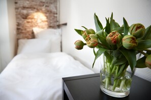A bed with white linens and a nightstand with a vase of tulips. - Hotel Liegeplatz 13 Kiel by Première Classe (Kiel)
