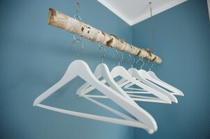 A wooden branch with white hangers against a blue wall.
