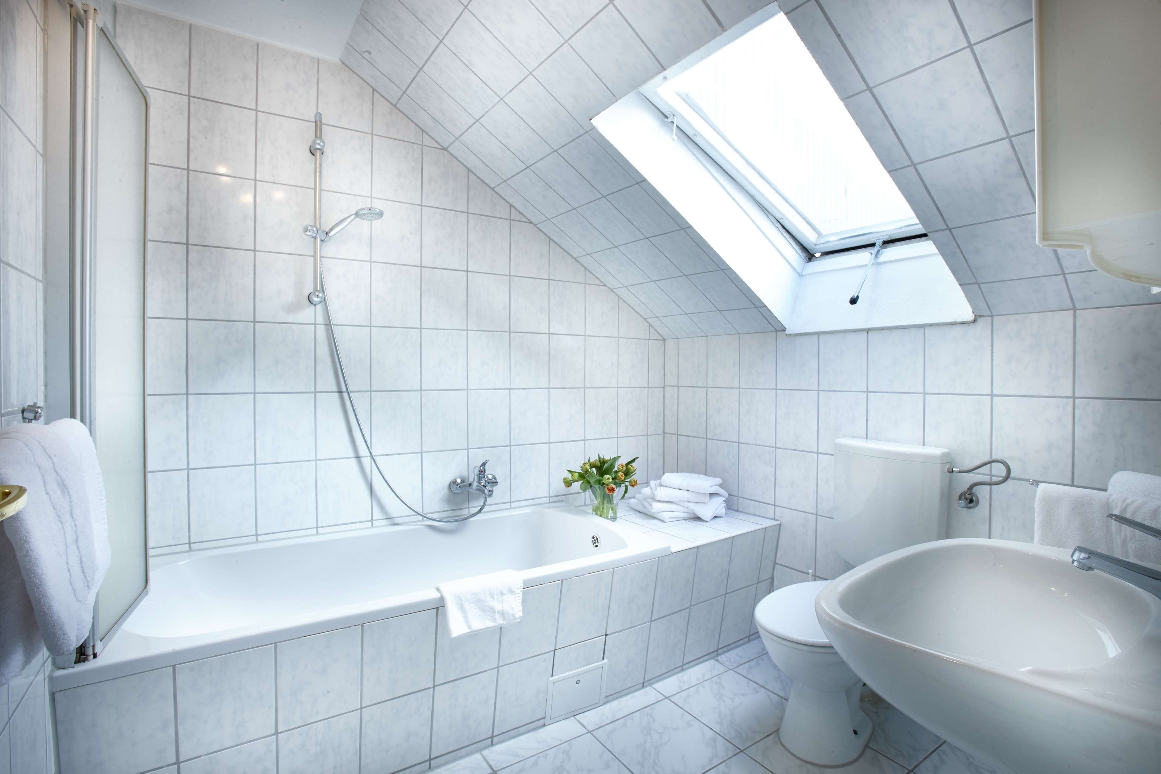 Ein modernes Badezimmer mit Dachfenster, einer Badewanne, einem Waschbecken und einer Toilette.